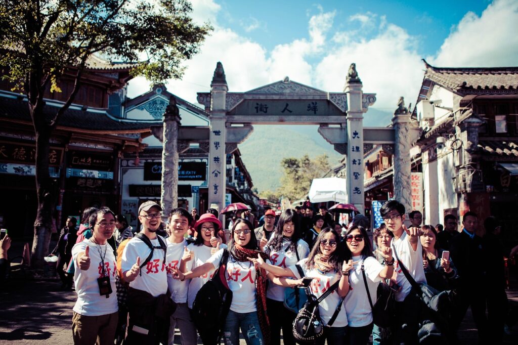 Group of people standing outside an archway, with Chinese writing on it